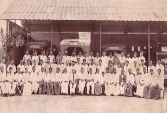 බස් සමාගමේ සේවකයන් පිරිසක් සිටින පැරණි ඡායාරූපයක් - බස් කිහිපයක් ද පසෙකින් දිස්වෙයි